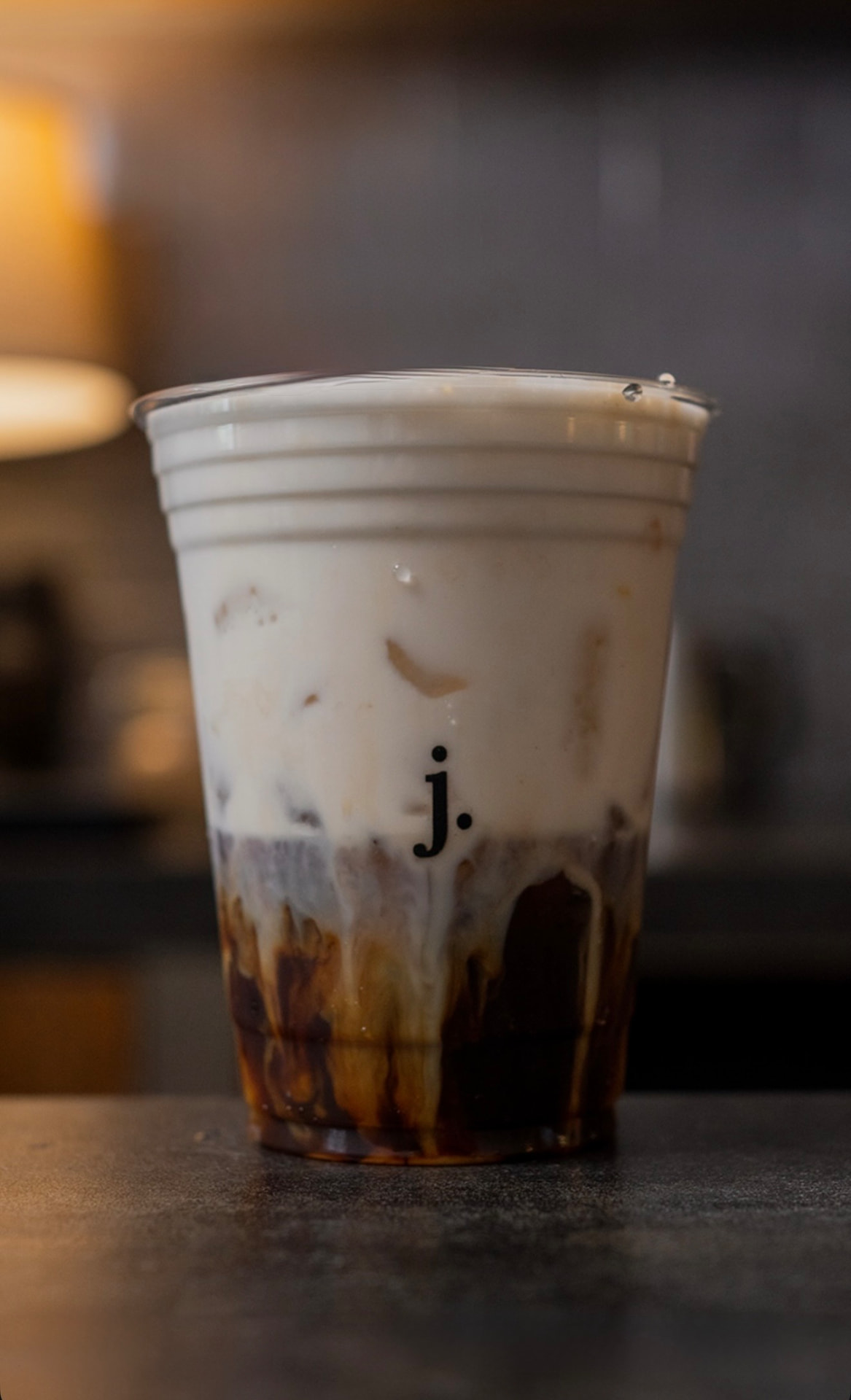 Vaso con la letra j. sobre la barra, con capas de café y leche